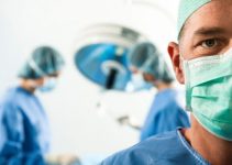 Doctor in scrubs in foreground with blurred people in scrubs in background during surgery possible medical malpractice